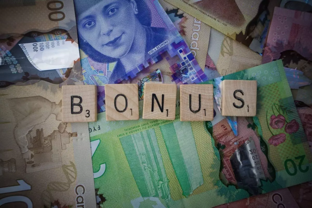 Das Woert "Bonus" in Scabble-Bausteinen vor Geldscheinen