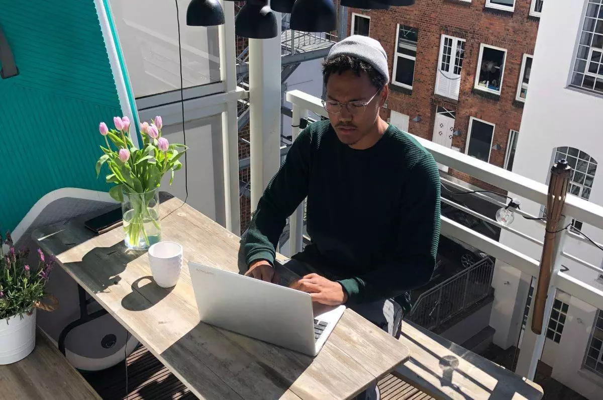 Ein Mann arbeitet mit Laptop auf dem Balkon